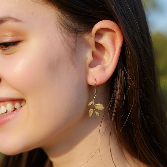 Close-up of a person wearing gold leaf earrings