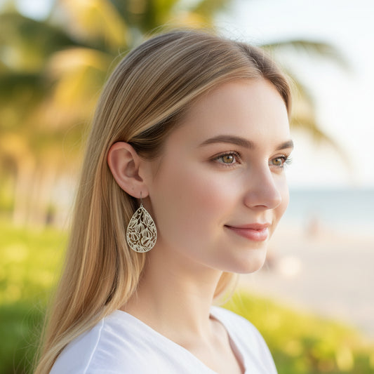 A pair of silver floral filigree teardrop dangle earrings with a polished stainless steel finish, designed for invisible clip-on wear.