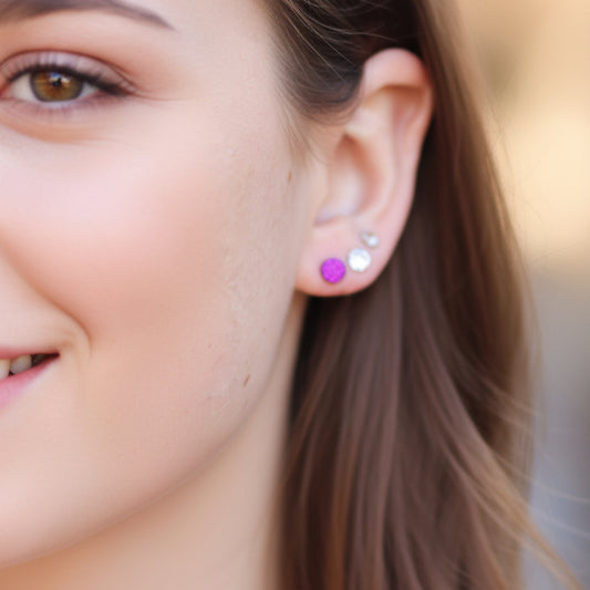 Close-up of an ear wearing a purple earring and a silver earring.