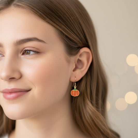 Close-up of an ear with pumpkin-shaped earrings and a small stud earring.