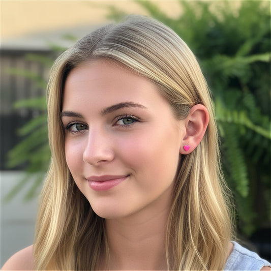 Close-up of a person wearing a pink heart-shaped earring with a blurred green background