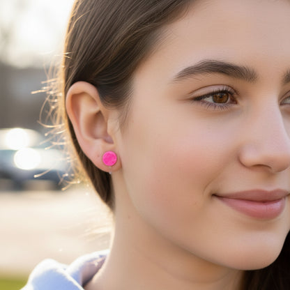 an ear model wearing a pink opalescent round clip on earring 