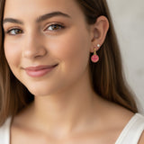 Close-up of an ear with pink smiley face earring and other accessories.