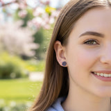Close-up of an ear wearing a colorful stud earring with a blurred background