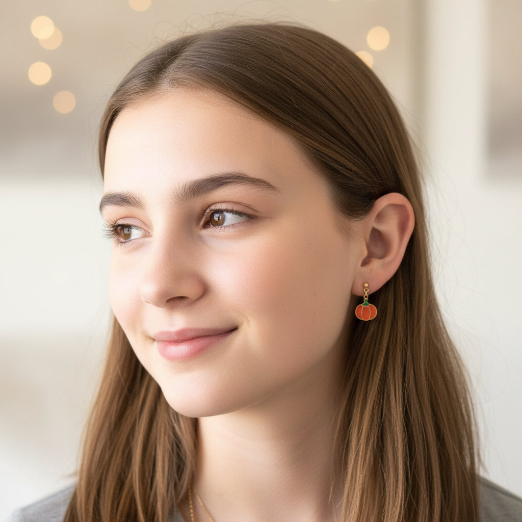 Close-up of an ear wearing a pumpkin-shaped earring with a blurred background
