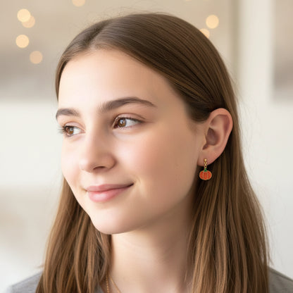 Close-up of an ear wearing a pumpkin-shaped earring with a blurred background