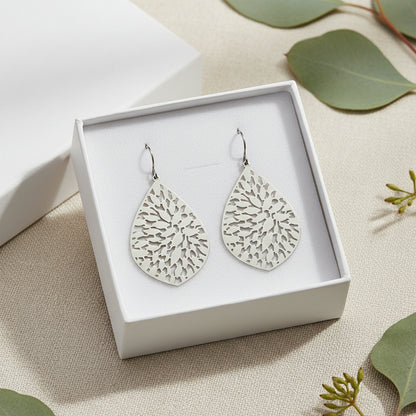 A pair of silver teardrop dangle earrings with a leaf-like pattern on the earring body.