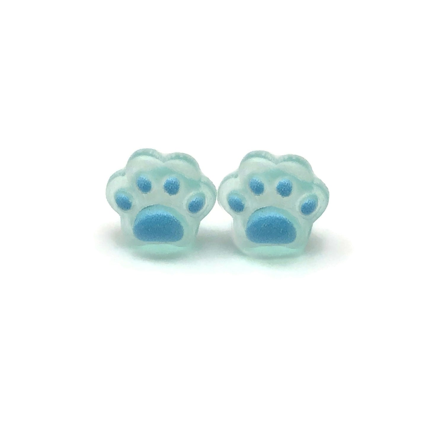 A pair of dainty paw print-shaped stud earrings in a beige color with brown details on a white background.
