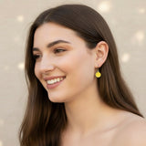 Close-up of an ear wearing a yellow smiley face earring with a blurred background
