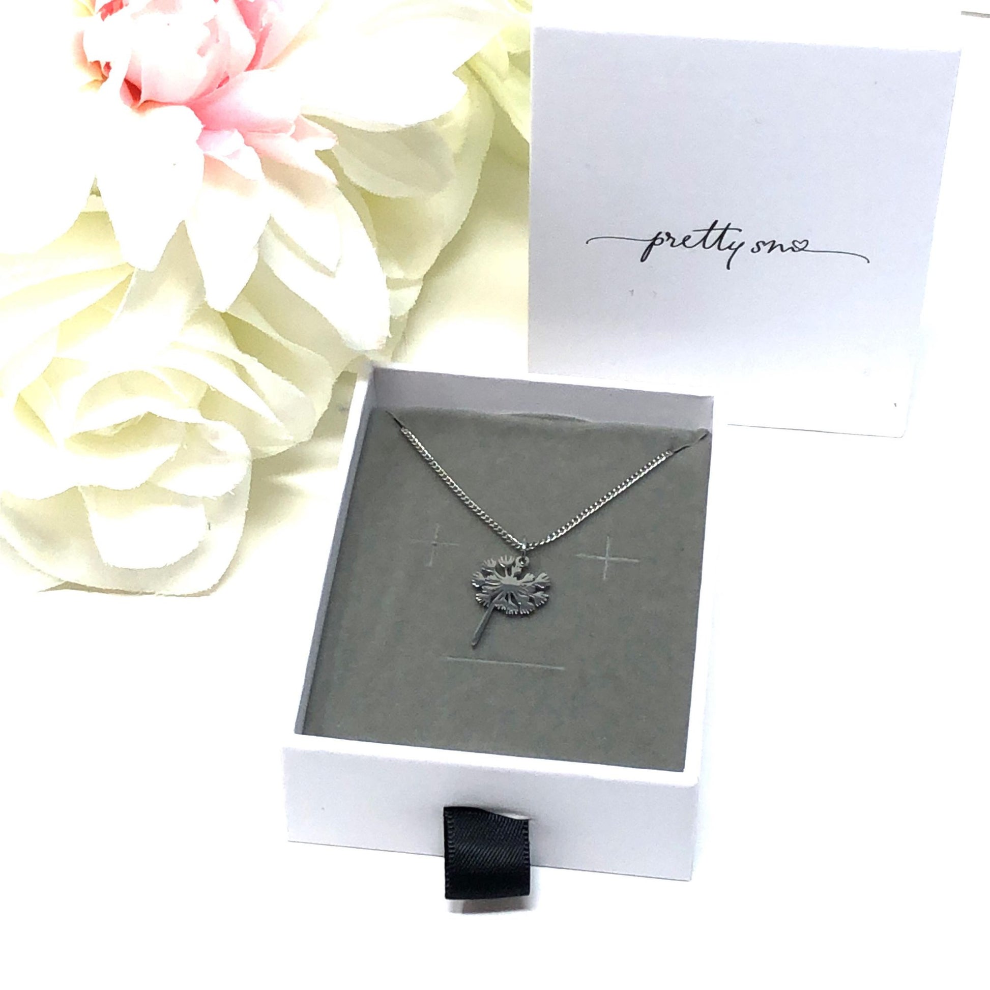 A dandelion flower necklace with a 18K gold PVD plated stainless steel chain and a lobster clasp in a gift box