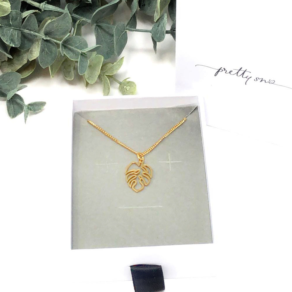 gold monstera charm on chain in gift box