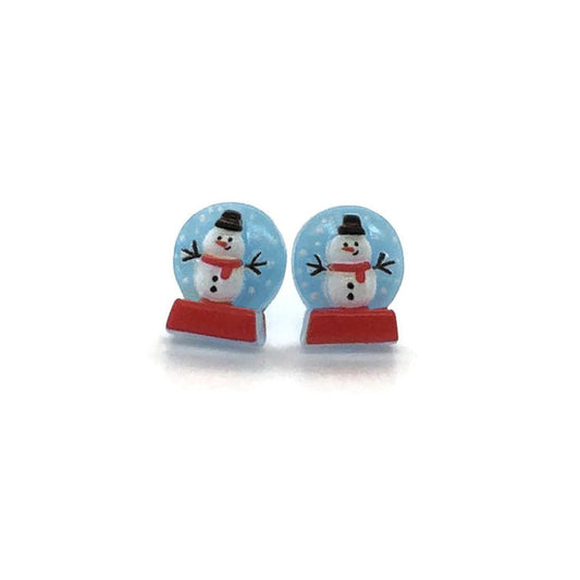 A pair of snow globe stud earrings with snowmen inside, featuring red bases and clearomes.