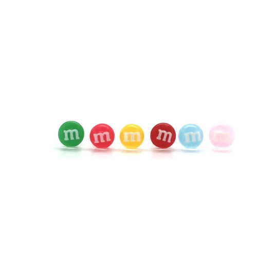 A series of dainty stud earrings in the colors of the M&M's candy, displayed from left to right in green, yellow, red, blue, and pink.