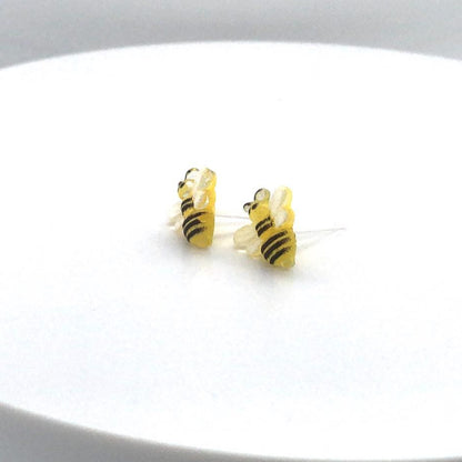 A pair of bee-shaped stud earrings made of resin, with yellow and black color scheme, displayed against a white background.