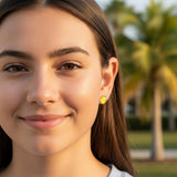Close-up of an ear with a lemon-shaped earring and another small earring.