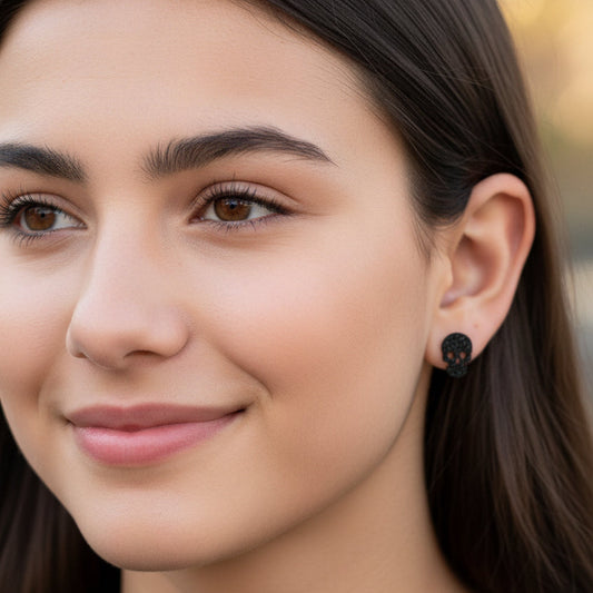 Close-up of an ear with black skull earring and clear gemstone earring.
