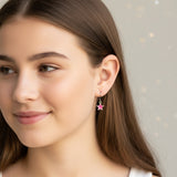 Close-up of an ear wearing a pink star-shaped earring with blurred background