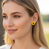 Close-up of a person wearing a yellow sunflower earring with a blurred background