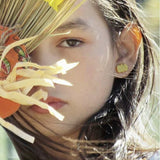 Close-up of a person wearing glitter pumpkin earrings with a blurred background