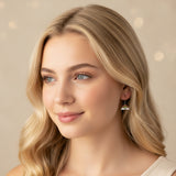 Close-up of an ear wearing a rainbow-shaped earring with a blurred background