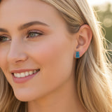 Close-up of a woman wearing blue earrings with a blurred natural background