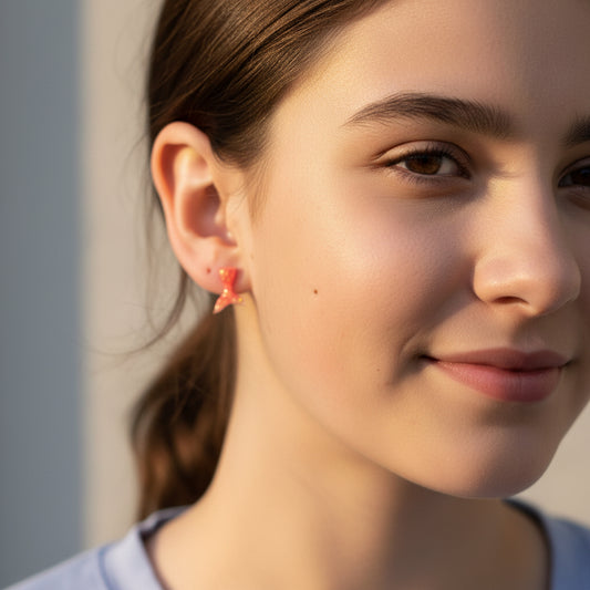 Close-up of an ear with a red mermaid tail earring and a small silver earring.