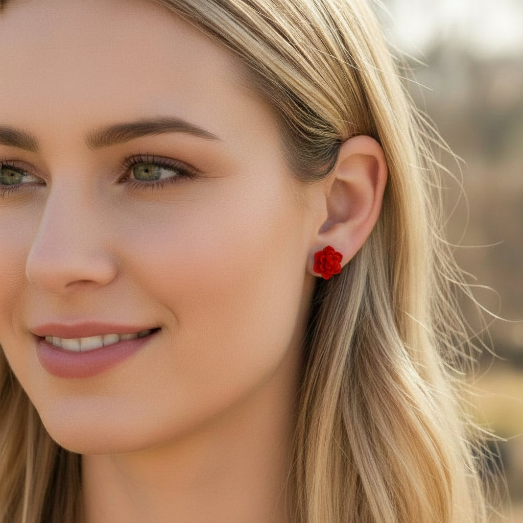 Red floral earring worn by a person with blurred background
