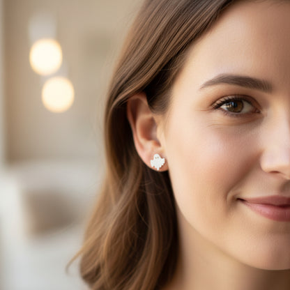Close-up of an ear with a white ghost-shaped earring and a rhinestone-shaped earring.