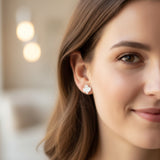 Close-up of an ear with a white ghost-shaped earring and a rhinestone-shaped earring.