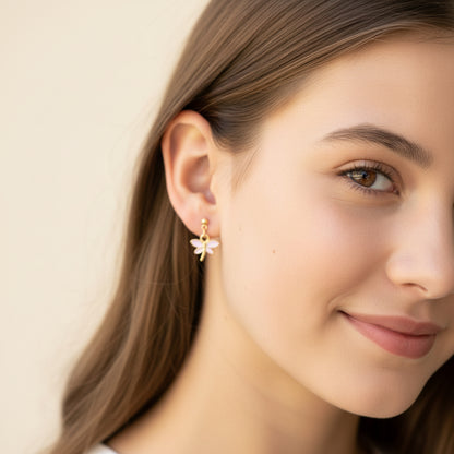Close-up of an ear wearing a gold earring with a pink gemstone.