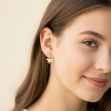 Close-up of an ear wearing a gold earring with a pink gemstone.