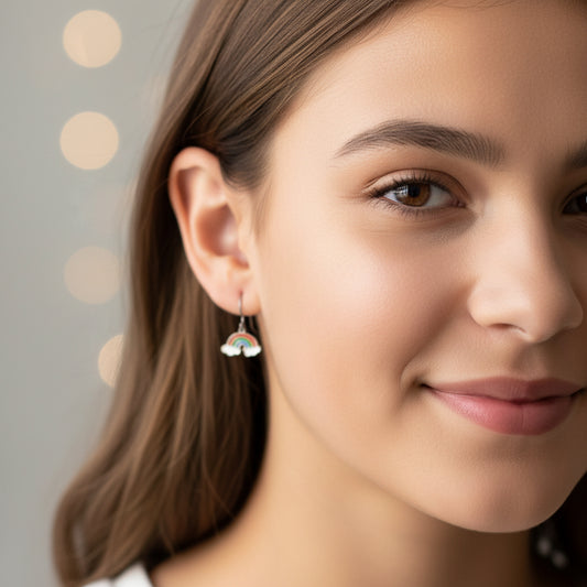 Close-up of an ear wearing a rainbow-shaped earring with a small hoop.