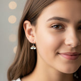 Close-up of an ear wearing a rainbow-shaped earring with a small hoop.