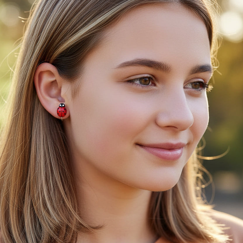 Close-up of a person wearing a red ladybug earring with a black dot.