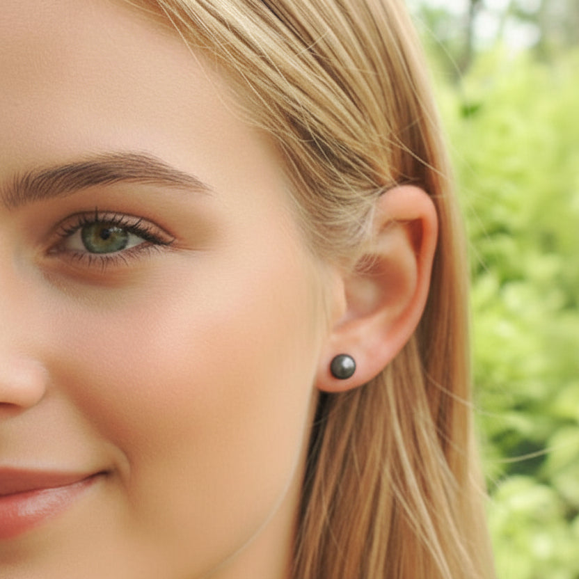 Close-up of a woman wearing a pearl earring with a blurred green background