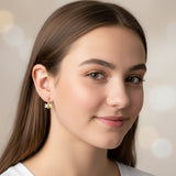 Close-up of an ear with gold bee-shaped earrings and small stud earrings.