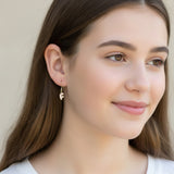 Close-up of an ear with a gold earring featuring the letter 'F'.