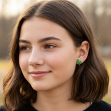Close-up of an ear with green glitter dinosaur clip on earrings.