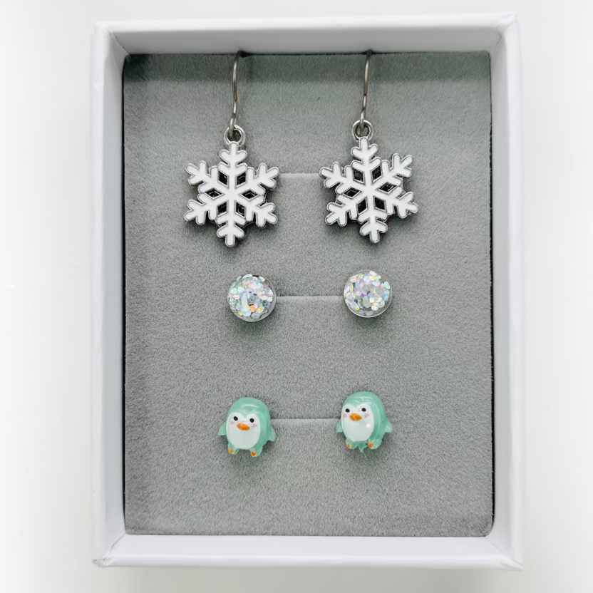 Set of snowflake earrings and penguin earrings in a display box.