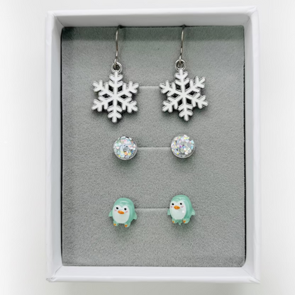 Set of snowflake earrings and penguin earrings in a display box.