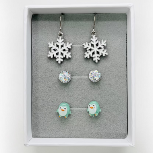Set of snowflake earrings and penguin earrings in a display box.