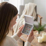 model opening a Set of 3 Christmas-themed earrings in a box