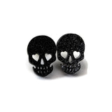 Black glitter skull-shaped earrings on a white background