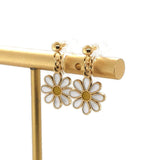 A pair of dangle earrings featuring a white and yellow daisy design on a silver hook.