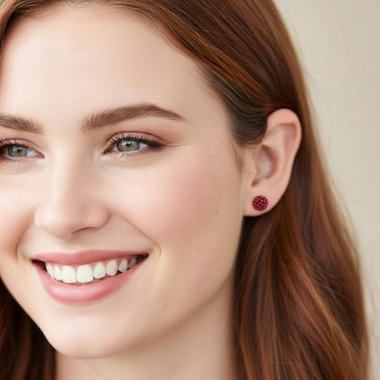 Close-up of a woman wearing red  earrings with a neutral background