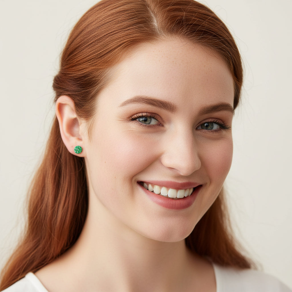 Woman wearing green earrings with a plain background