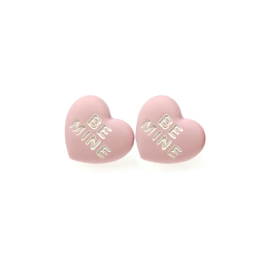 A pair of pink conversation heart stud earrings with the phrase 'BE MINE' printed on them.