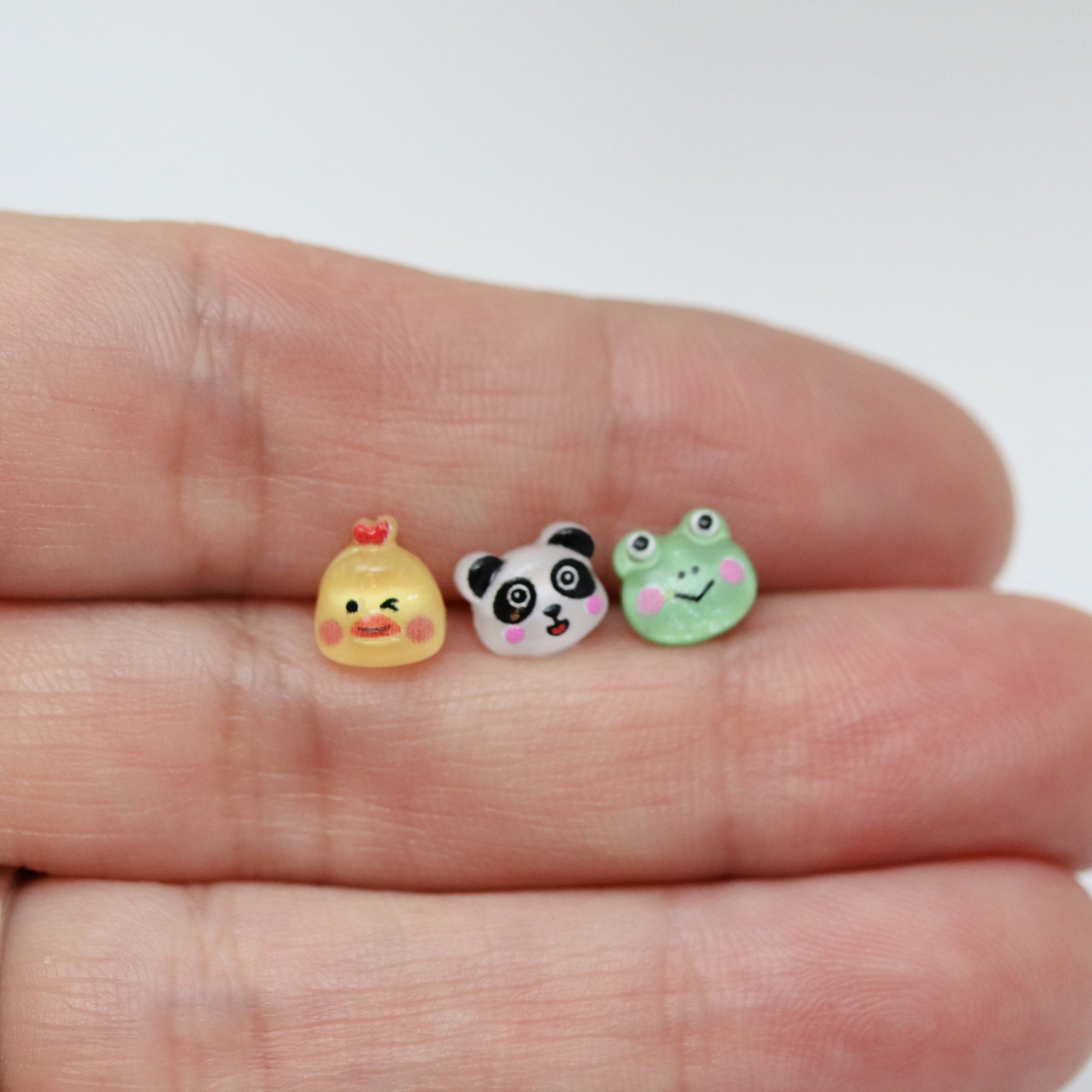 chicken, panda and frog earring in hand