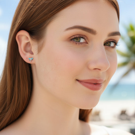 A pair of stainless steel dainty dragonfly stud earrings with a blue and gold PVD coating, featuring flat screw-on backs.