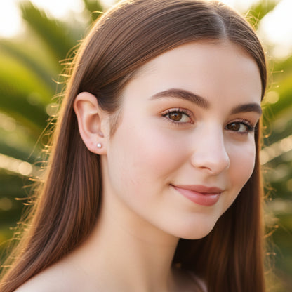 A pair of screw-back, simulated pearl earrings with a gold PVD coating on ear